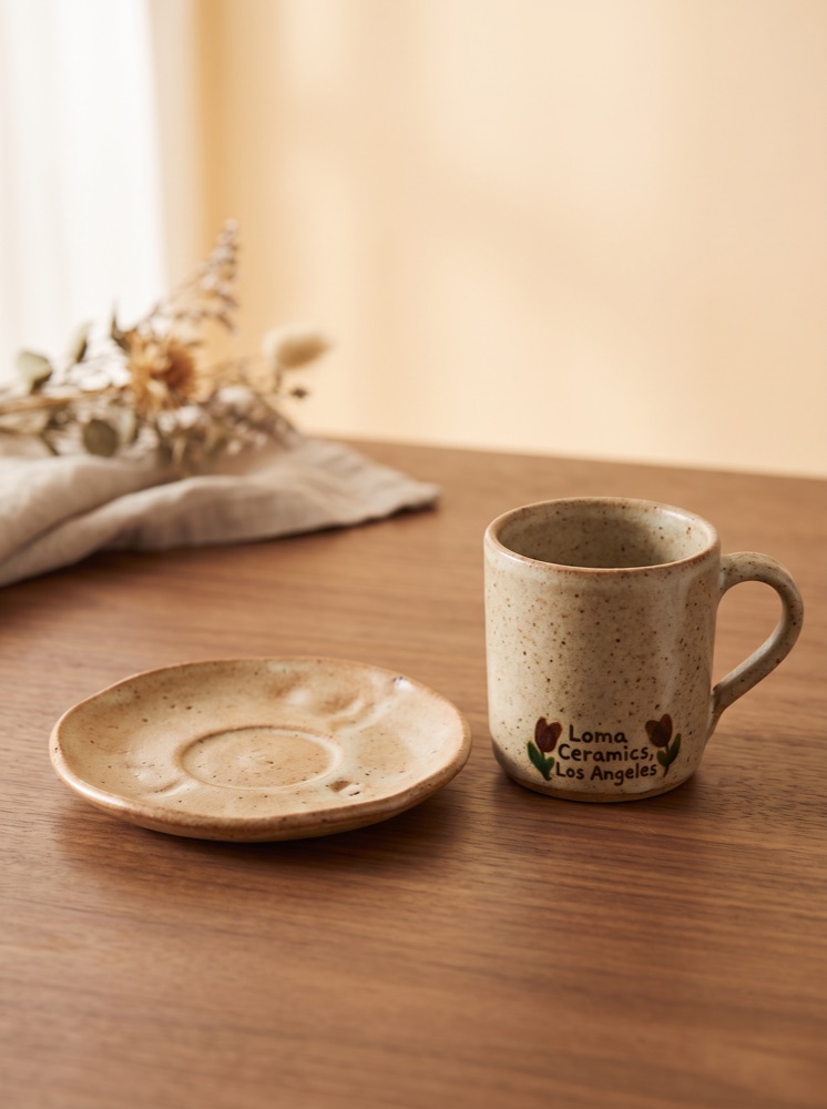 A speckled stoneware mug and saucer by Loma Ceramics